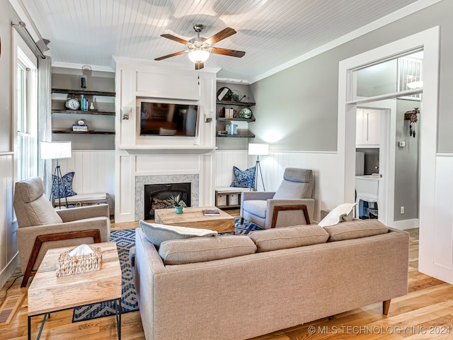 living room featuring ornamental molding, built in features, light hardwood / wood-style floors, and ceiling fan