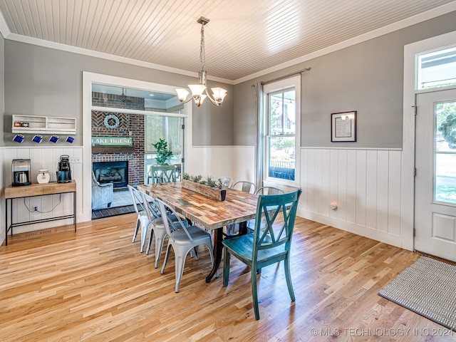 dining room with a chandelier, wooden ceiling, light hardwood / wood-style flooring, a fireplace, and crown molding