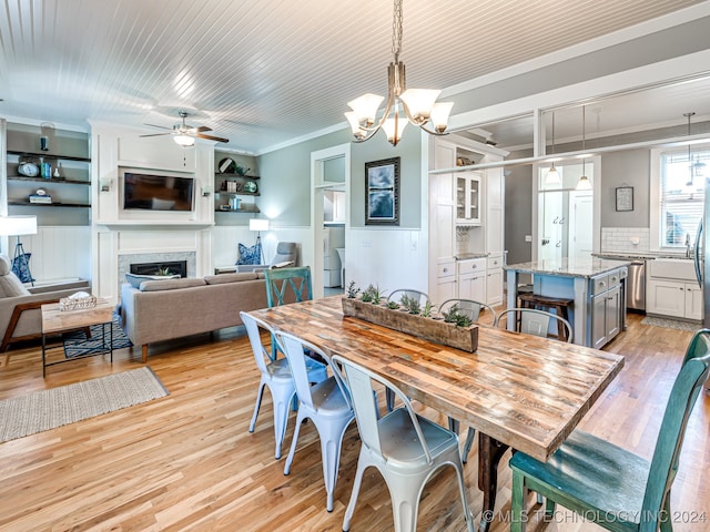 dining room with crown molding, light hardwood / wood-style flooring, and ceiling fan with notable chandelier