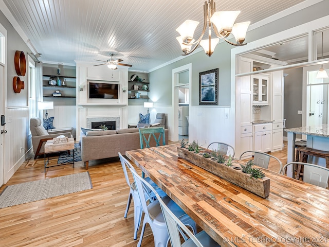 dining room with light hardwood / wood-style flooring, ornamental molding, ceiling fan with notable chandelier, and built in shelves