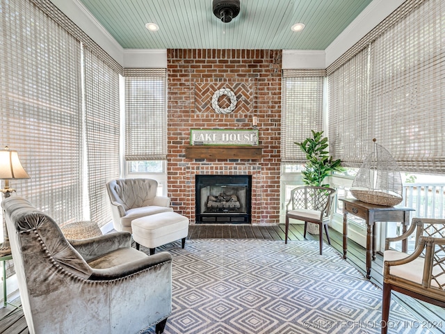 living room with a brick fireplace, ornamental molding, and a wealth of natural light