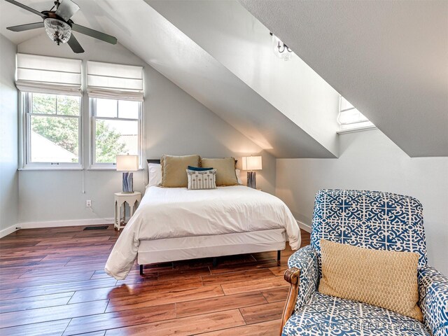 bedroom featuring visible vents, baseboards, vaulted ceiling, and wood finished floors