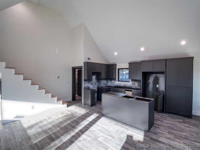 kitchen featuring hardwood / wood-style floors, a center island, high vaulted ceiling, gray cabinets, and tasteful backsplash