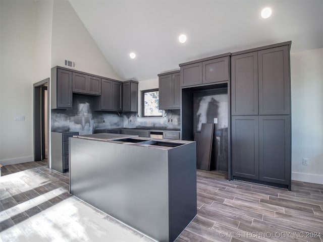 kitchen featuring a center island, decorative backsplash, gray cabinets, and light wood-type flooring