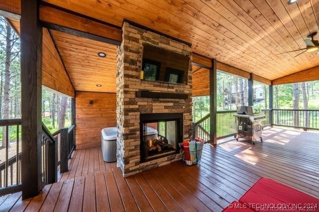 interior space featuring a stone fireplace, wooden ceiling, hardwood / wood-style flooring, and vaulted ceiling