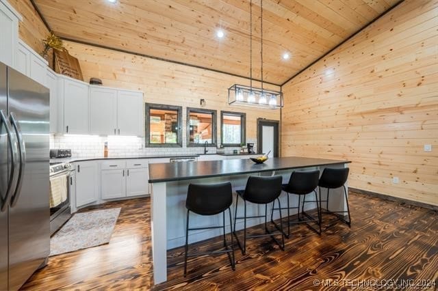 kitchen featuring stainless steel fridge, white cabinets, a kitchen island, and dark wood-type flooring