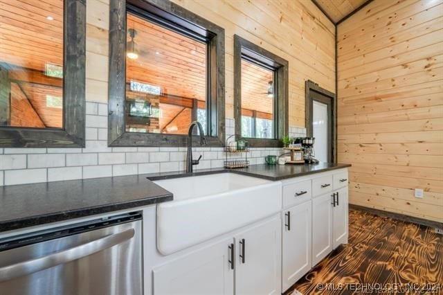 kitchen with white cabinets, dishwasher, backsplash, wood walls, and dark hardwood / wood-style flooring