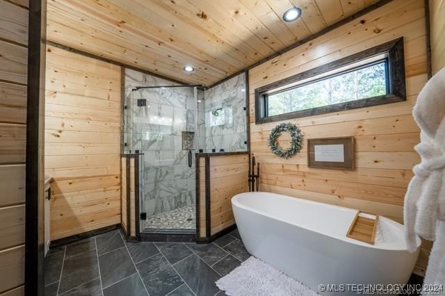 bathroom with tile patterned flooring, shower with separate bathtub, wooden walls, and wooden ceiling