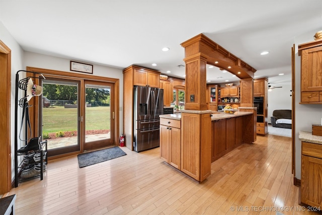 kitchen with a center island, stainless steel fridge, oven, and light hardwood / wood-style floors