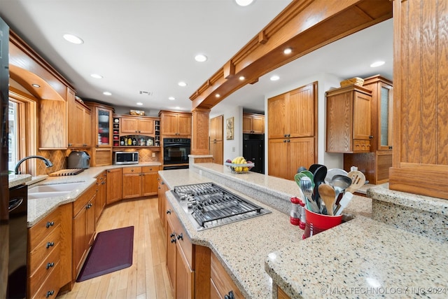 kitchen featuring light stone counters, sink, stainless steel appliances, and light hardwood / wood-style floors