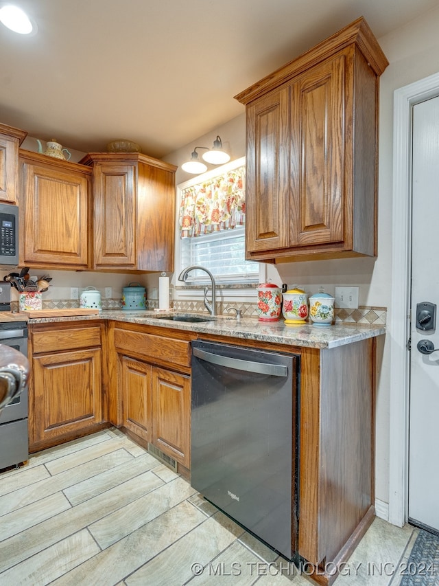 kitchen with range, sink, black dishwasher, light stone counters, and light tile patterned floors