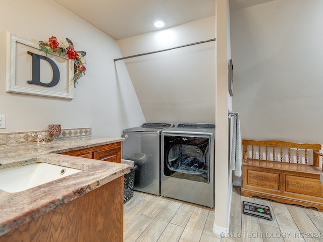 laundry room with light wood-type flooring, sink, and separate washer and dryer