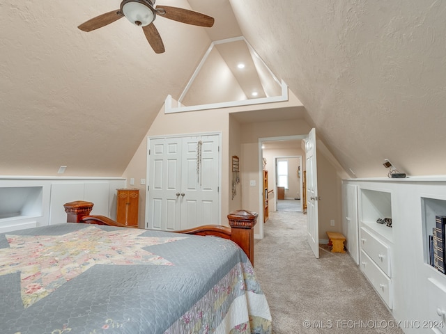 bedroom with a closet, ceiling fan, light colored carpet, vaulted ceiling, and a textured ceiling