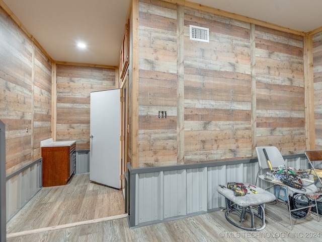 interior space with light wood-type flooring and wooden walls