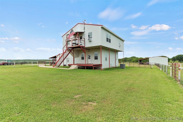 back of house with a rural view, a yard, and a wooden deck