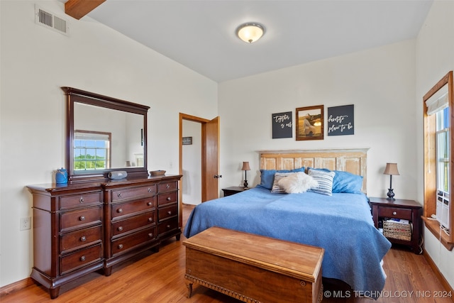 bedroom featuring hardwood / wood-style floors and beam ceiling