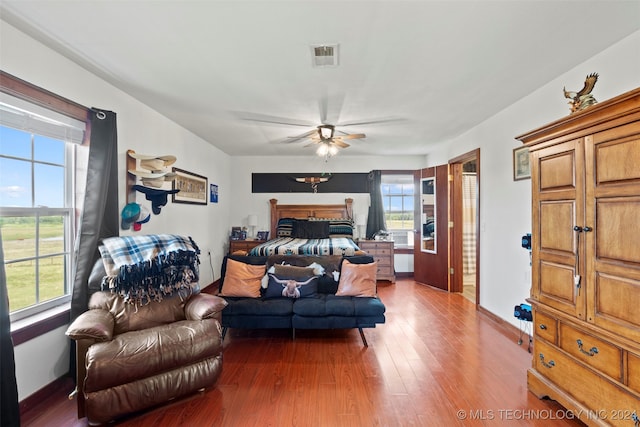 bedroom featuring ceiling fan, hardwood / wood-style flooring, and multiple windows