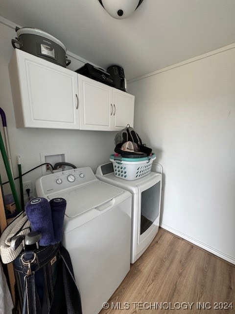 laundry room featuring washing machine and clothes dryer, cabinets, and wood-type flooring