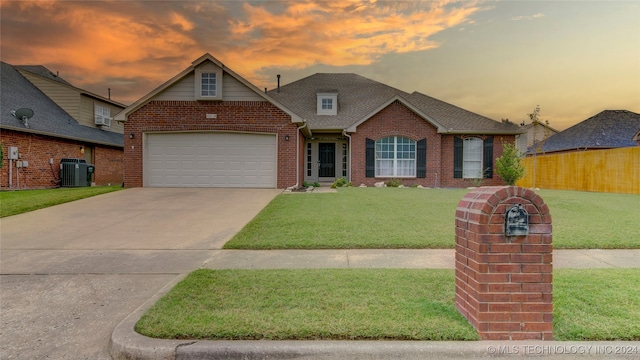 view of front of house with central air condition unit, a garage, and a lawn