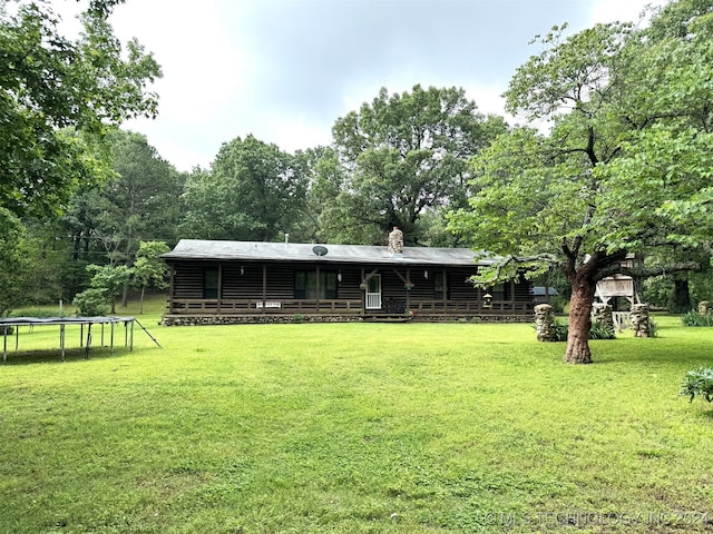 back of property featuring a trampoline and a yard