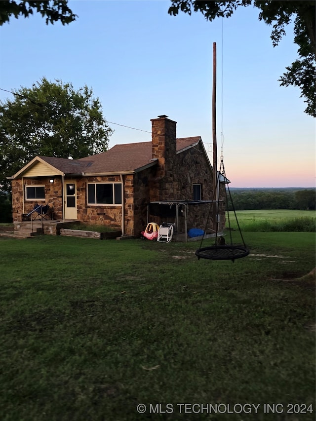 back house at dusk featuring a yard