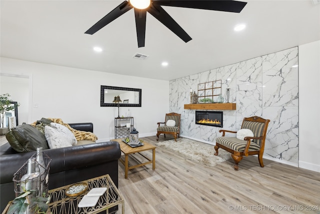 living room featuring light wood-type flooring, ceiling fan, and tile walls