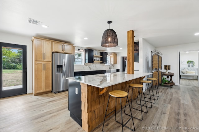 kitchen featuring stainless steel fridge with ice dispenser, light hardwood / wood-style flooring, light brown cabinets, light stone counters, and decorative light fixtures