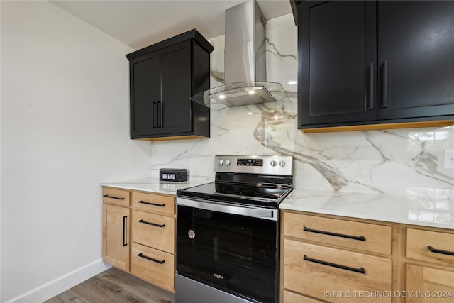 kitchen featuring backsplash, electric stove, light stone countertops, wall chimney exhaust hood, and wood-type flooring