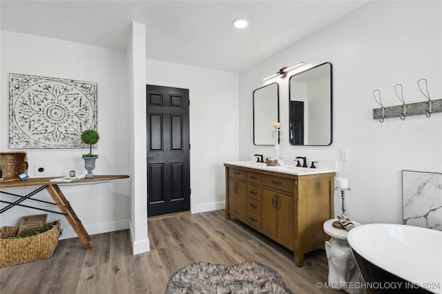 bathroom with dual vanity, a bathing tub, and hardwood / wood-style floors