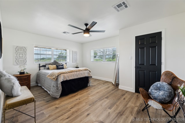 bedroom with multiple windows, ceiling fan, and hardwood / wood-style floors