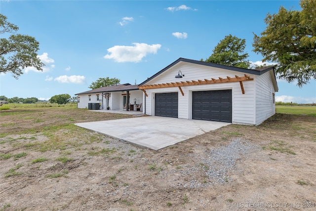 view of front of property featuring a garage, central AC, and an outdoor structure