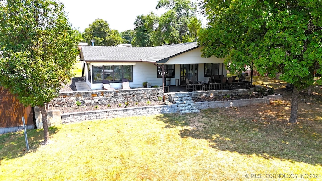 back of property featuring covered porch and a lawn