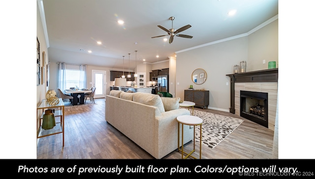 living area featuring recessed lighting, crown molding, a tiled fireplace, and wood finished floors