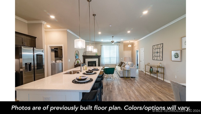 kitchen with a center island with sink, washer and clothes dryer, a glass covered fireplace, open floor plan, and stainless steel fridge with ice dispenser