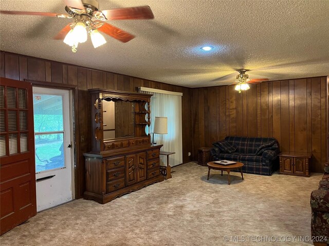 living room with a textured ceiling, ceiling fan, and carpet flooring