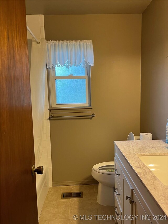 bathroom with tile patterned flooring, vanity, toilet, and a shower