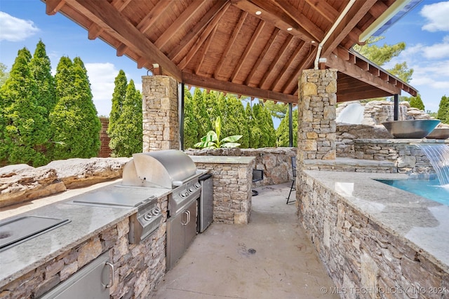 view of patio / terrace with pool water feature, an outdoor kitchen, and grilling area