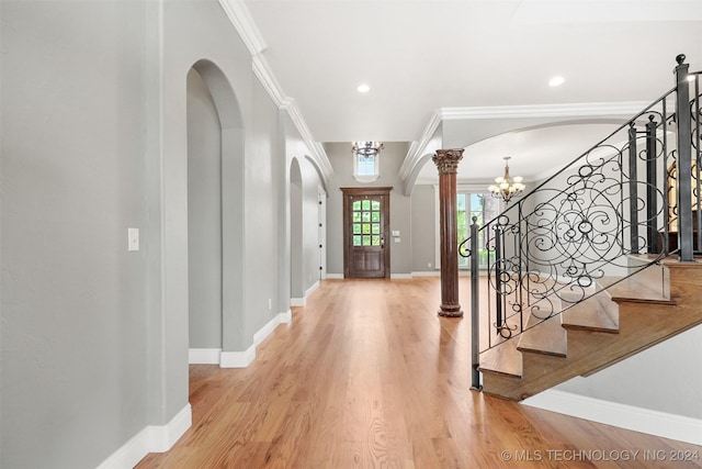 entryway featuring wood-type flooring, decorative columns, and crown molding