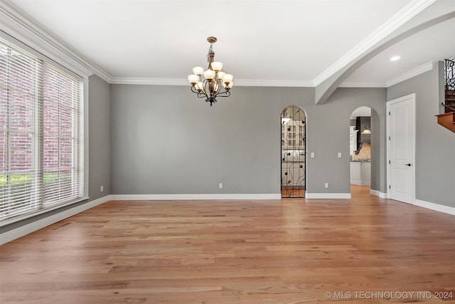 spare room featuring a chandelier, crown molding, and light hardwood / wood-style flooring