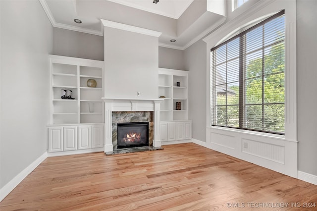 unfurnished living room with a healthy amount of sunlight, a premium fireplace, and light hardwood / wood-style flooring