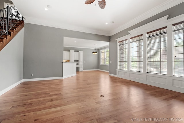 unfurnished living room with hardwood / wood-style floors, ceiling fan, and crown molding