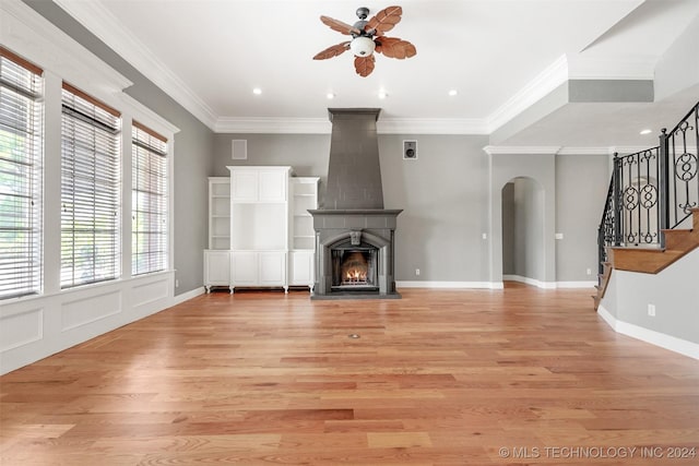 unfurnished living room with ceiling fan, a fireplace, light hardwood / wood-style floors, and ornamental molding