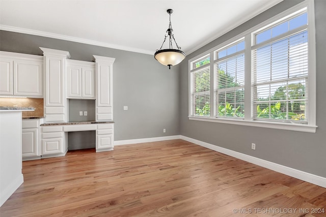 kitchen with backsplash, white cabinets, crown molding, hanging light fixtures, and light hardwood / wood-style floors