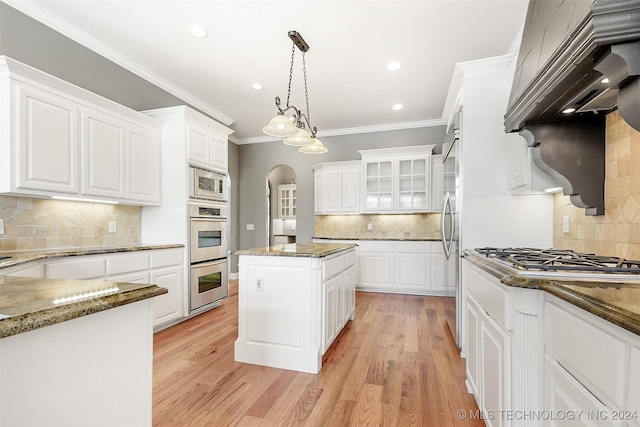 kitchen with white cabinets, stainless steel appliances, light hardwood / wood-style flooring, and dark stone countertops