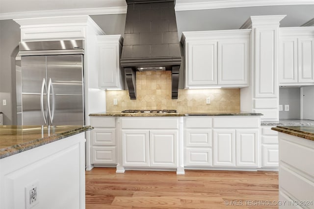 kitchen with dark stone countertops, white cabinetry, light wood-type flooring, and appliances with stainless steel finishes