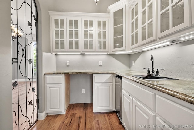 kitchen with light stone countertops, sink, light hardwood / wood-style flooring, a chandelier, and white cabinets