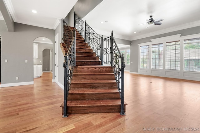 staircase featuring a wealth of natural light, wood-type flooring, and ornamental molding