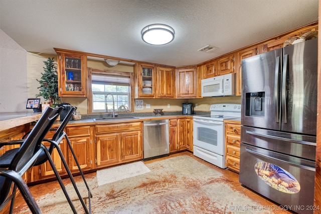 kitchen with a textured ceiling, sink, and stainless steel appliances