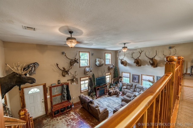 carpeted living room with a textured ceiling and ceiling fan