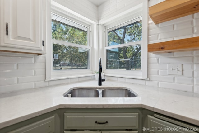 kitchen with dishwasher, sink, light stone counters, decorative backsplash, and white cabinetry